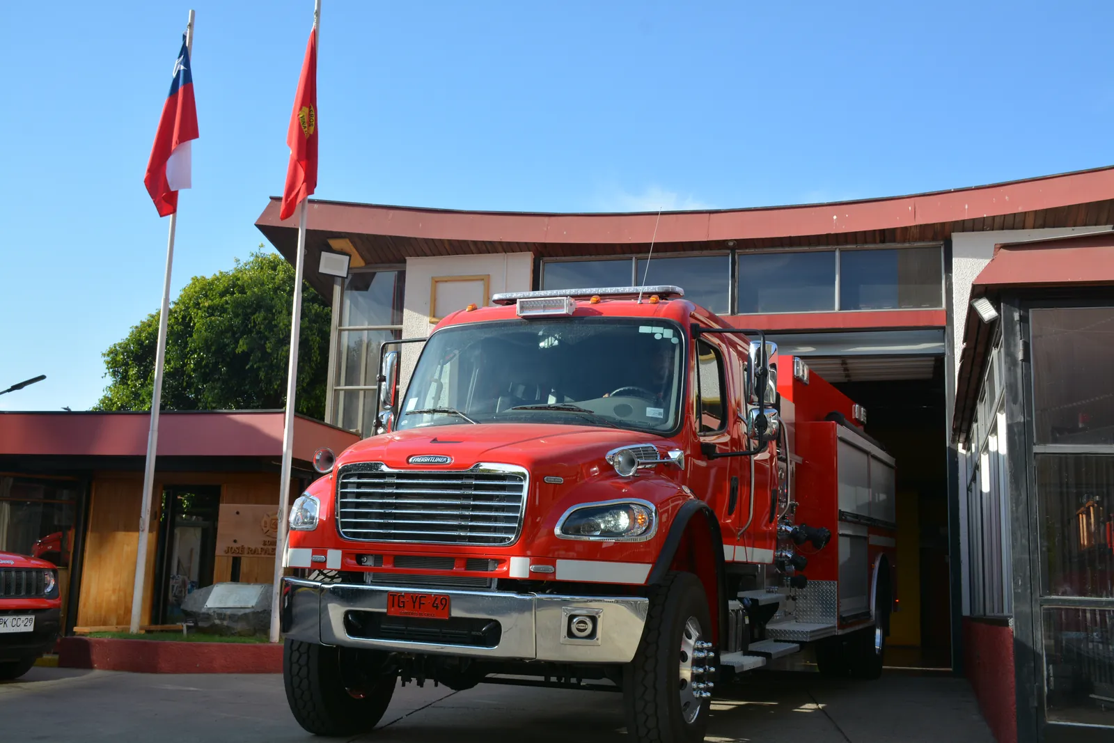 La nueva 43, una Freightliner roja de abastecimiento, frente al cuartel con las banderas de Chile y de la compañía.