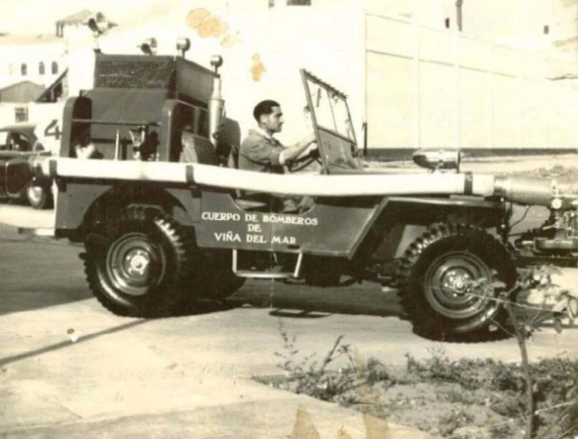 Fotografía sepia de un jeep con «Cuerpo de Bomberos de Viña del Mar» en el costado y un conductor al volante.